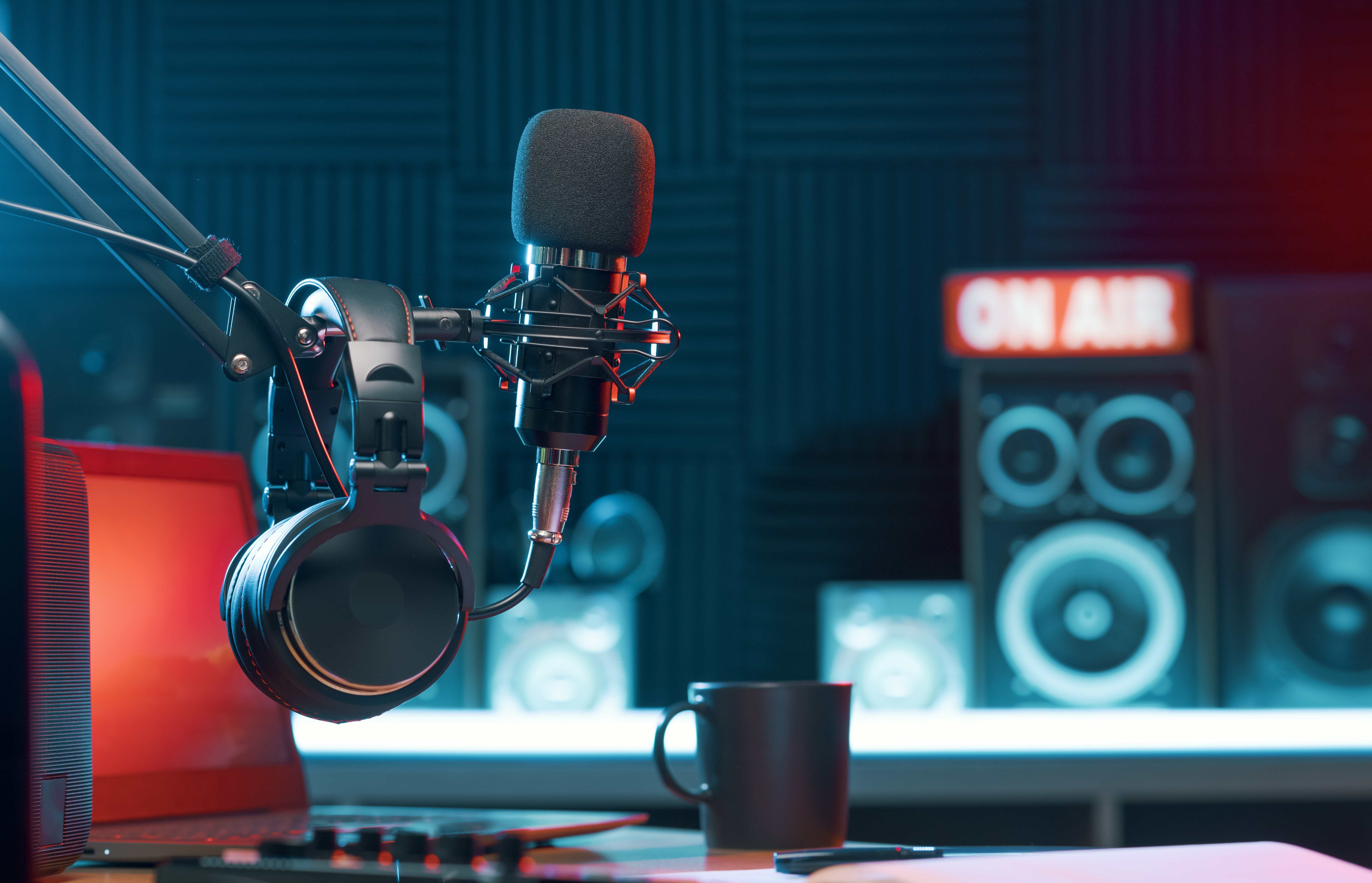 Home studio podcast interior. Microphone, laptop and on air lamp on the table, close-up